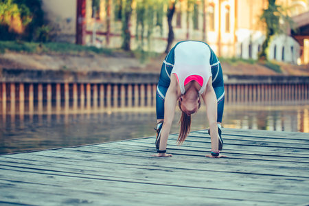 Girl in bridge pose, young woman doing exercises outdoor in nature, by the river.