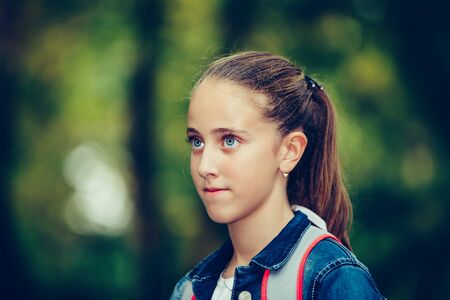 Close up outdoor portrait of a cute schoolgirl with backpack.の写真素材