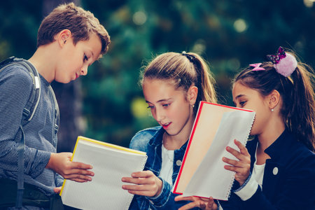 Back to school. Children with backpacks are having fun, talking, reading a book.Group of elementary...