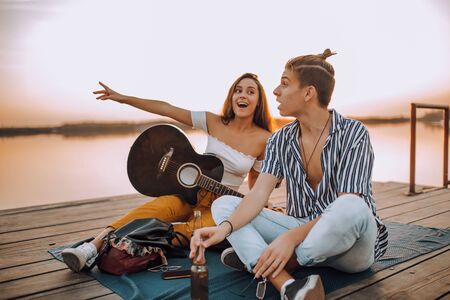 Happy young cheerful couple in love having fun by the river. Girl showing something interesting to her boyfriend.の写真素材