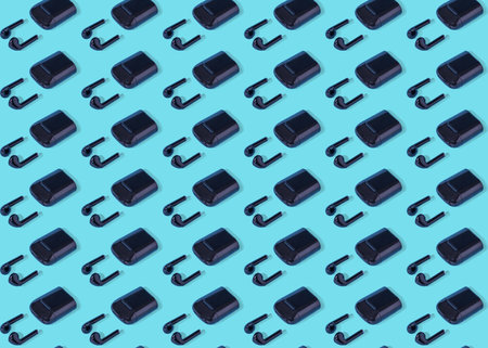 Pattern of wireless earbuds or earphones of black isolated on blue background. Minimal composition background.の写真素材