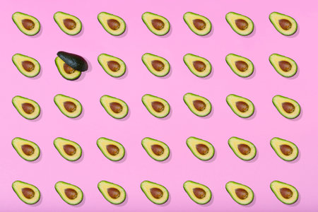 Avocado pattern on light pink background. Top view. Pop art minimal design, creative summer food concept. Green avocados, minimal flat lay style.の写真素材