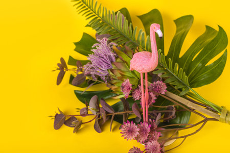 Trendy Summer idea made with pink flamingo figure and different tropical plants on bright...