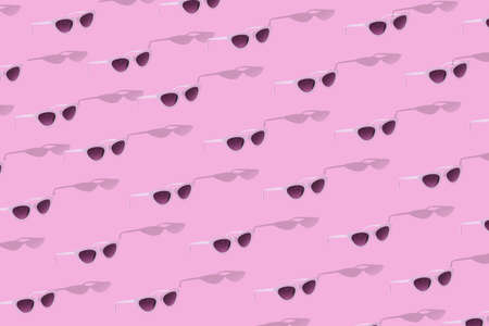 Trendy pattern made of white sunglasses with shadow on pastel pink background. Minimal summer concept.の写真素材