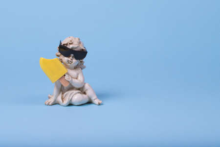 Minimal creative idea with a white angel in sunglasses and ice cream on a bright blue background. Funny art design. Copy spaceの写真素材