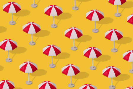 Creative idea, a pattern of colorful umbrellas on a illuminating yellow background. Minimal trendy summer vacation concept.の写真素材