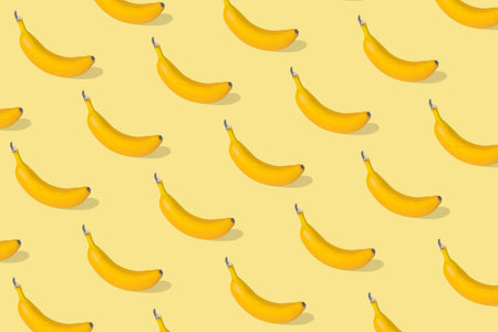 Trendy Summer pattern made with fresh banana fruit on illuminating yellow background. Minimal summer...