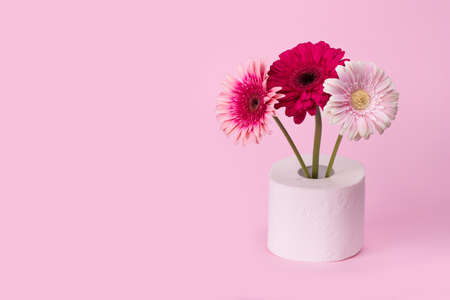 Gerbera flowers in vase made of toilet paper on pastel pink background. Minimal funny spring or summer floral concept. Humorous Art concept of nature, Birthday,  Valentines, Women's, Wedding Day. Copy spaceの写真素材