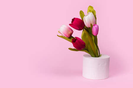 Tulips flowers in vase made of toilet paper on pastel pink background. Minimal funny spring or summer floral concept. Humorous Art concept of nature, Birthday,  Valentines, Women's, Wedding Day. Copy spaceの写真素材