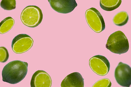 Frame of sliced fresh green lime isolated on light pink background. Vitamins, healthy diet and detox concept. Sliced lime floating in the air. Minimal creative concept  fruit concept with free space for text.の写真素材