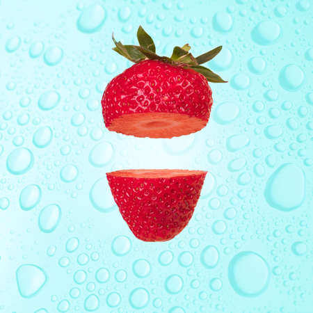 Floating levitating ripe strawberry on a wet  blue background with water drops. Vitamins, fresh healthy food concept. Minimal fruit idea. Sliced strawberry floating in the air. Creative concept with flying fruits.の写真素材