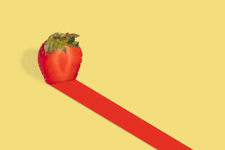 Half of red strawberry leaves red track on illuminating yellow background. Vitamins, fresh healthy food concept. Minimal fruit idea.  Suitable for advertising, marketing, adsの写真素材