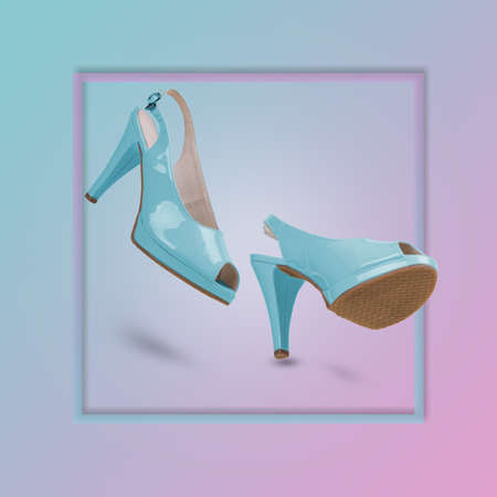 Elegant blue sandals with high heels on a trendy background illuminated by a blue and pink color gradient. Creative minimal concept of femininity, trend and fashion. Suitable for advertising, marketing, ads. Copy spaceの写真素材