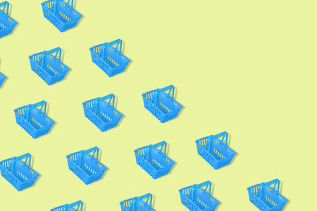 Outstanding pattern with blue empty shopping baskets isolated on a yellow background. Modern minimal...