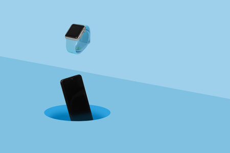 Smart watch and mobile phone falling into a hole on pastel blue background. Minimal fashion...