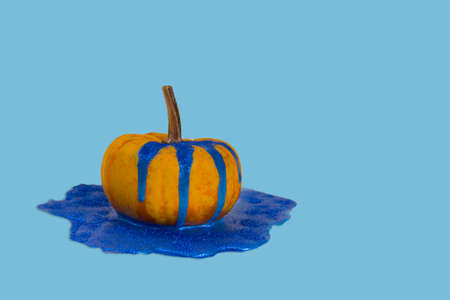 Creative autumn idea. Fresh pumpkin with shiny dripping and melting paint on f background. Minimal Holiday and season concept background. Copy space.の写真素材