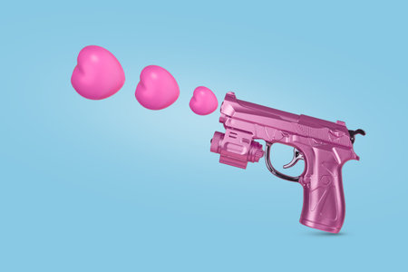 Pink gun firing hearts on blue background. Creative valentines or romantic concept. Minimal love background.の写真素材