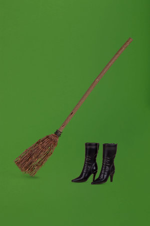 Witch broom and black shoes on a green background. Minimal holiday celebration horror concept. Creative Halloween minimal arrangement.の写真素材
