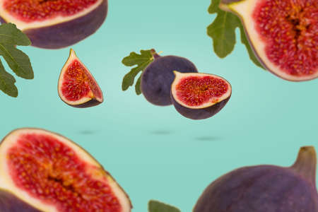 Trendy minimal food concept with fresh ripe whole and sliced figs flying in air isolated on pastel green background. Creative food concept. Vegetarian diet idea.の写真素材