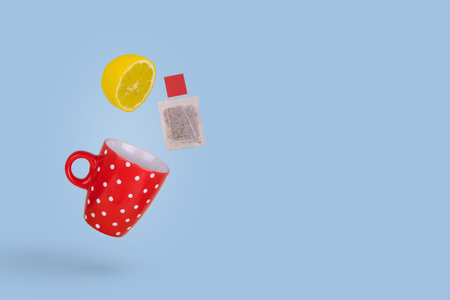 Creative concept red tea cup with flying tea bag and lemon slice. Minimal creative style.の写真素材