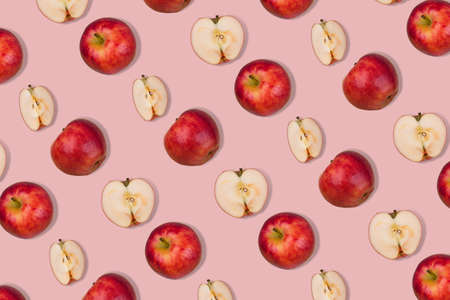 Outstanding pattern of fresh whole apple and halves on  pastel pink background. Minimalist isometric food concept.  Flat layの写真素材