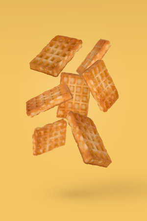 Soft waffles flying in air isolated on a yellow background. Creative food concept.