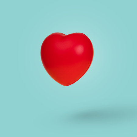 Creative idea with red floating heart in the air on pastel blue background. Minimal symbol of love...