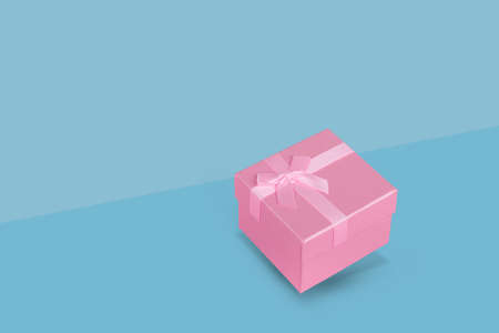 Pink gift box on a pastel blue background. Christmas concept art. Minimal New Year or birthday idea with copy space.の写真素材