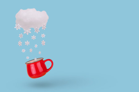 Creative concept with cloud, falling winter snowflake and mug on pastel blue background. Minimal...