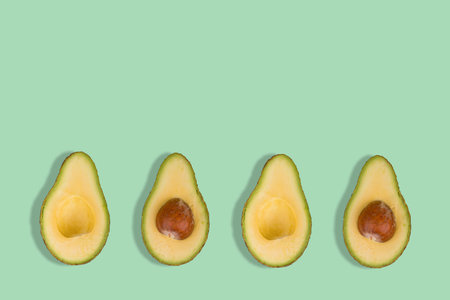 Sliced avocado on bright green background. Top view. Banner. Pop art design, creative summer food...