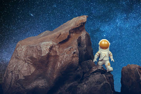 Determined Astronaut with gold visor and white Spacesuit on rock surface with space background.の写真素材