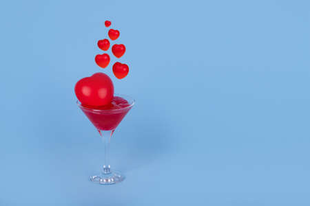 Valentine cocktail with red hearts isolated on a blue background. Creative love concept. Valentines Day. Trendy, minimalist card with copy space.の写真素材