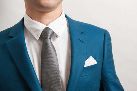 man in indigo suit with silver necktie, white shirt and pocket square, close upの写真素材