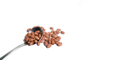 Close up. brown peanuts with stainless steel spoon isolated on white background. Empty space for...