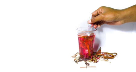An asian man's hand is stirring herbal drink with a spoon. with some spice around it. herbal drink isolated on a white backgroundの写真素材