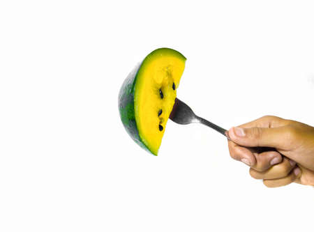 hand holding a fork stuck in delicious and healthy yellow watermelon. isolated white backgroundの写真素材