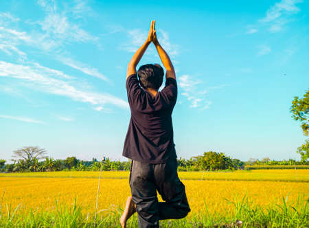 Young asian man doing yoga exercise for healthy life. Asian man meditating with peaceful nature in the morningの写真素材