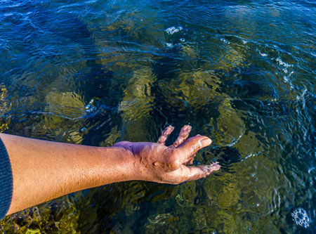 Hand of an asian man touching the water in the ocean. World water concept, clean water environment, environmental health, natural sea water cleanliness concept. World Oceans Dayの写真素材