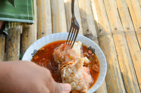 Hand holding a fork to eat the delicious Mie Pentol Bakso or meatball soup in the White bowl. Traditional Food of a Bakso Indonesian .Focus on meatball, Noisy, exposure, similar othersの写真素材