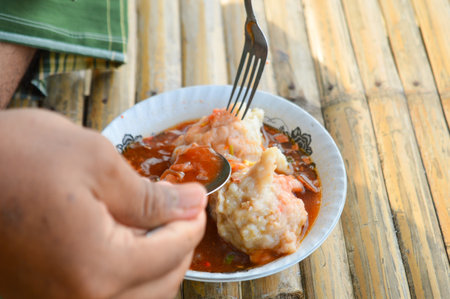 Hand holding a fork to eat the delicious Mie Pentol Bakso or meatball soup in the White bowl. Traditional Food of a Bakso Indonesian. Focus on meatball.の写真素材