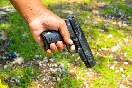Closep up of The hand of a security man, policeman, terrorist, thief, is carrying a gun and ready to shoot. Crime concept, Military, crime shooting. focus on gun, noisy, exposure, similar othersの写真素材