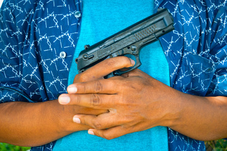 Man's hand holding a gun. Concept, despair, surrender, solitude, failure, death execution. focus on gun, noisy, exposure, similar othersの写真素材