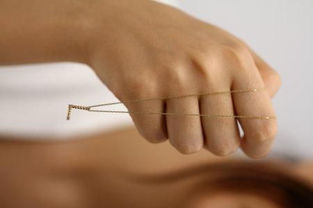 Close-up of a woman's hand holding a gold chain.の写真素材