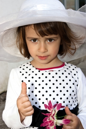 Portrait of beautiful girl with white hat and raised thumbsの写真素材