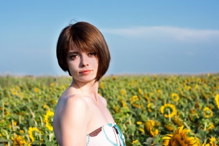 Portrait of a young beautiful woman in a field with sunflowersの写真素材