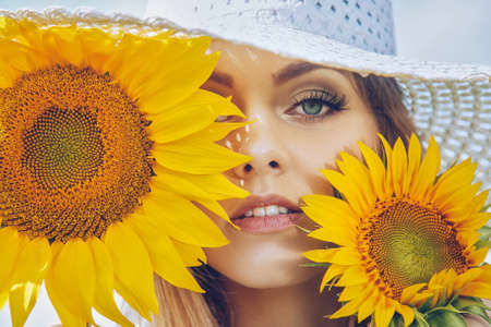 Portrait of young beautiful blond girl with stylish make-up and sunflowerの写真素材