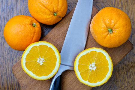 Whole and sliced oranges on a wooden board on the table