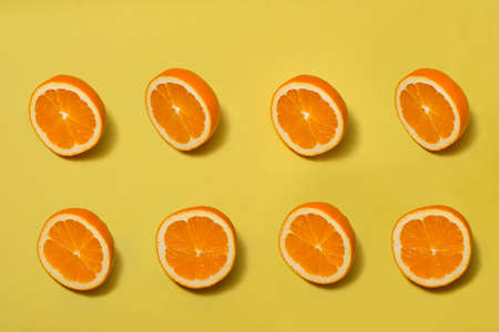 Orange top view with halves ripe orange on yellow backgroundの写真素材