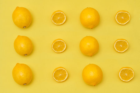 Lemon top view with halves and whole ripe lemons on yellow backgroundの写真素材