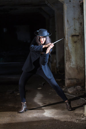 Warrior girl in blue dark suit with hat and sword in action